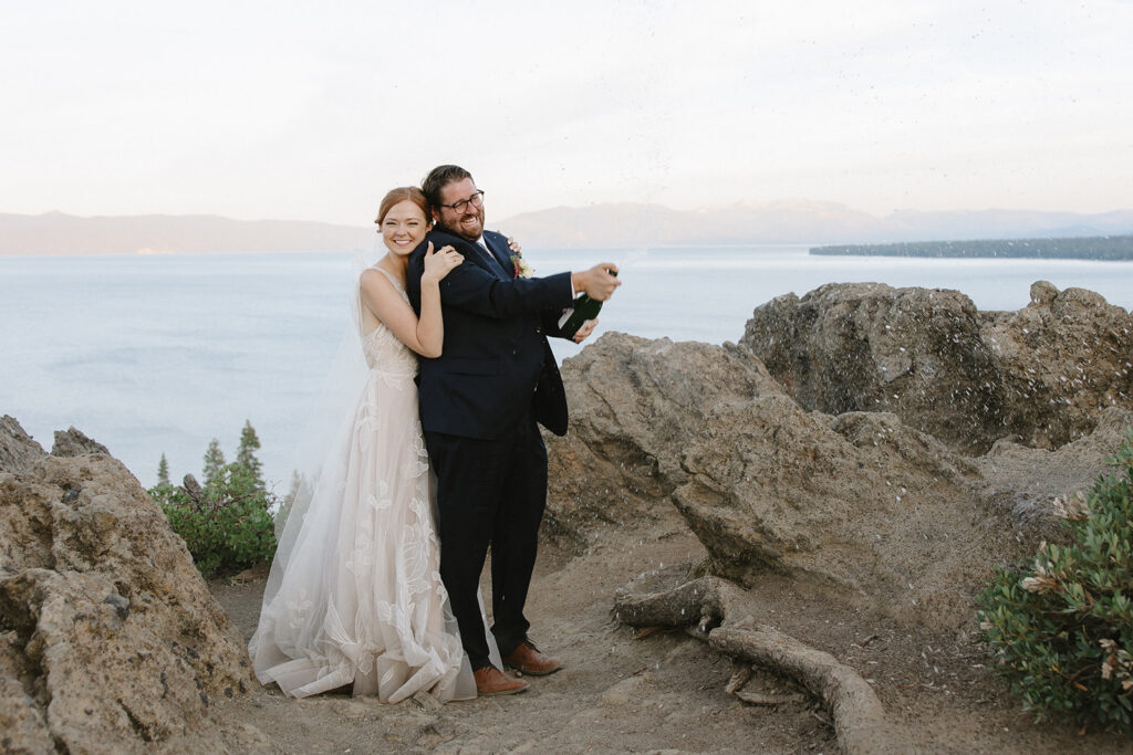 playful bride and groom popping champagne at an overlook during their lake tahoe elopement