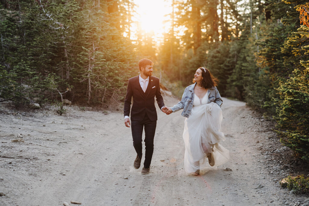 bride and groom running hand in hand through the forest in lake tahoe