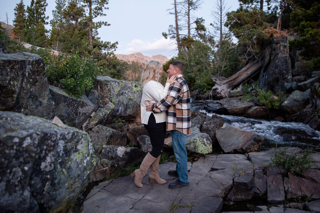 playful couple in Lake Tahoe surrounded by lush landscape and running water