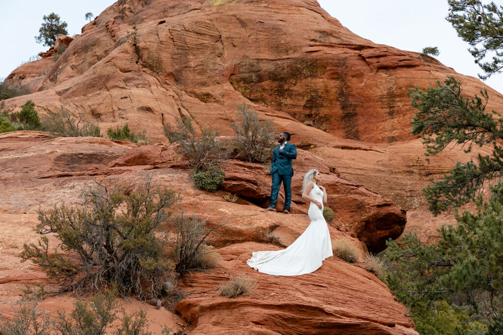 elopement couple standing on a red rock formation as they elope in sedona arizona