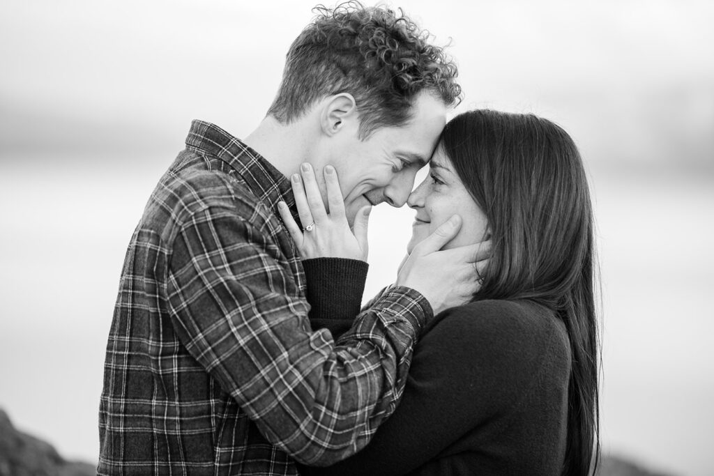 A couple shares a sweet moment  standing on a rocky cliff with a view of Lake Tahoe 