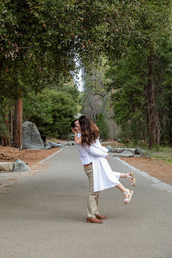 romantic couple on a road with waterfall and forest views in the backdrop in Yosemite