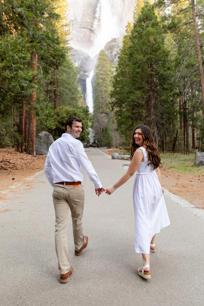 romantic couple on a road with waterfall and forest views in the backdrop in Yosemite