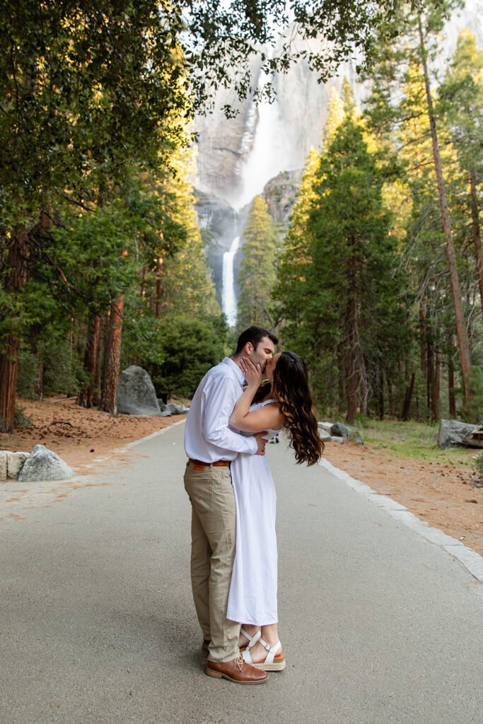 romantic couple on a road with waterfall and forest views in the backdrop in Yosemite