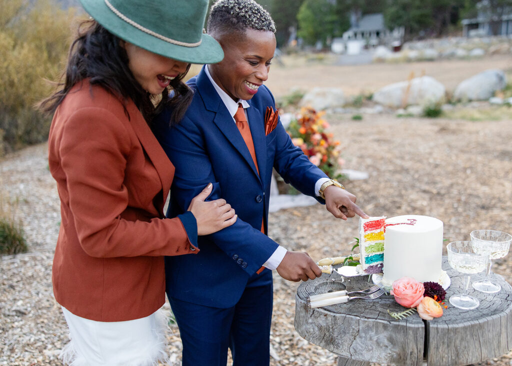 lgbtq couple cutting their rainbow wedding cake