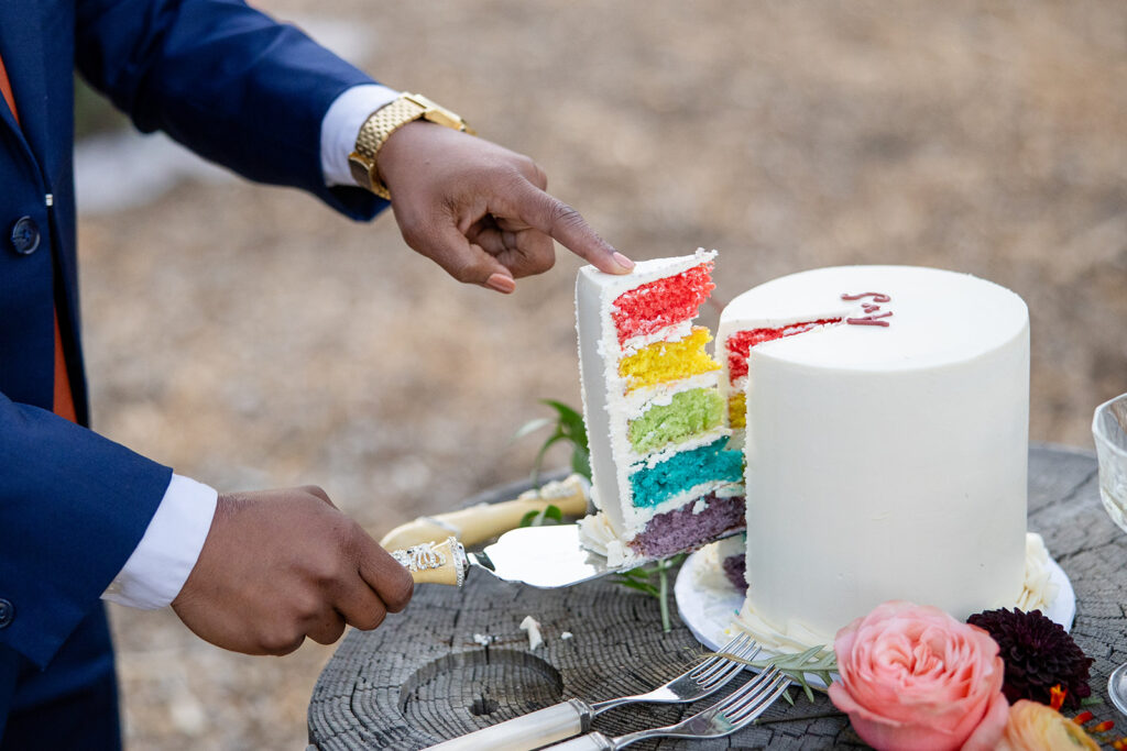 lgbtq couple cutting their rainbow wedding cake
