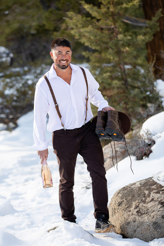 groom hiking to the getting ready location through a snowy trail