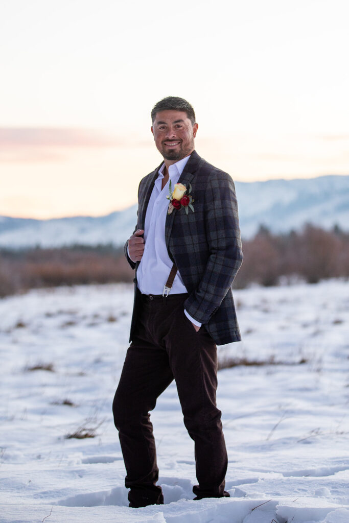 winter elopement groom standing outside in a snowy field with mountain views in lake tahoe
