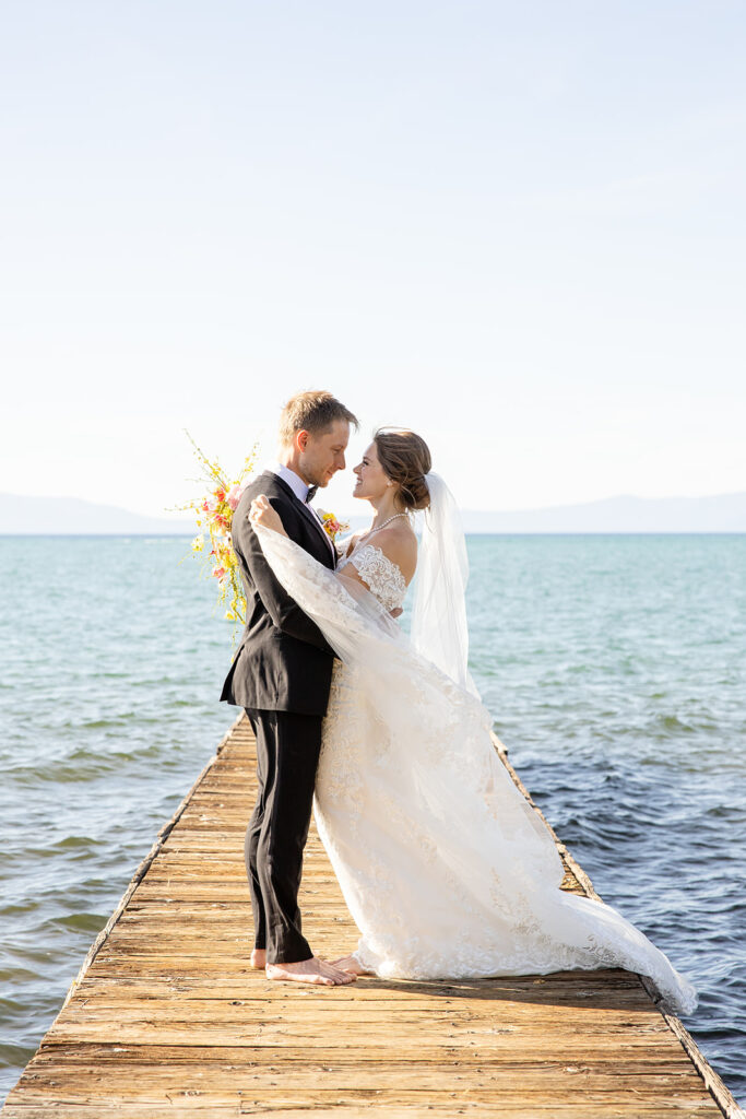 romantic barefoot bride and groom holding each other on the dock at lake tahoe 