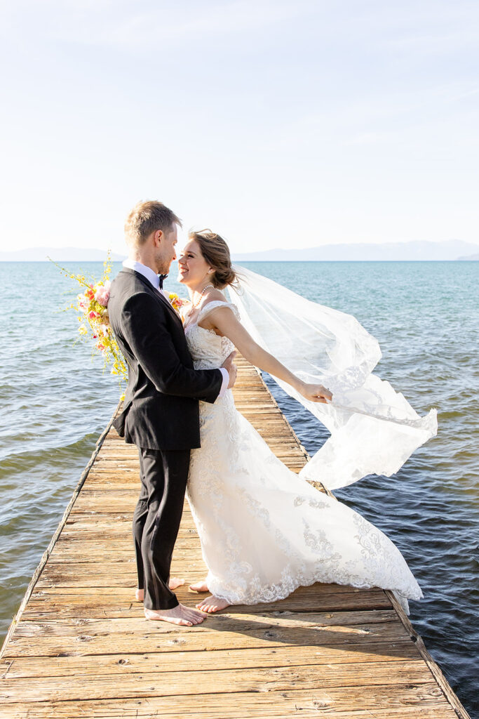 romantic barefoot bride and groom holding each other on the dock at lake tahoe 