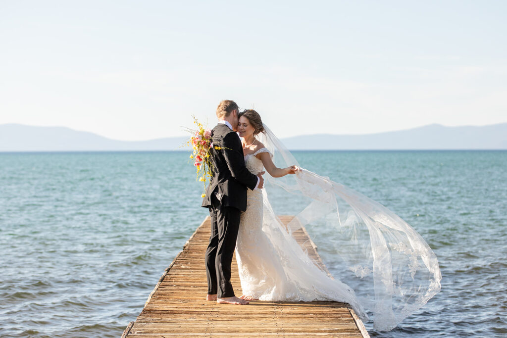 romantic barefoot bride and groom holding each other on the dock at lake tahoe 