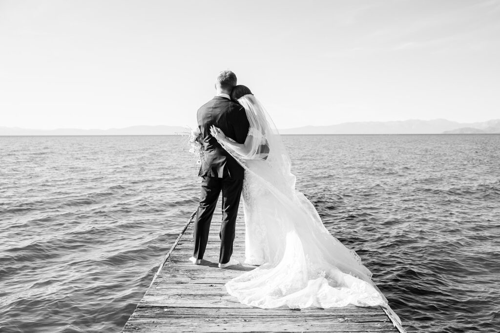 romantic barefoot bride and groom holding each other on the dock at lake tahoe 
