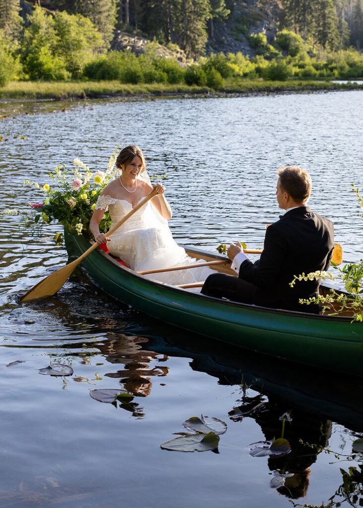 Bride and groom paddling in a canoe during their Lake Tahoe canoe wedding photos at Lily Lake.