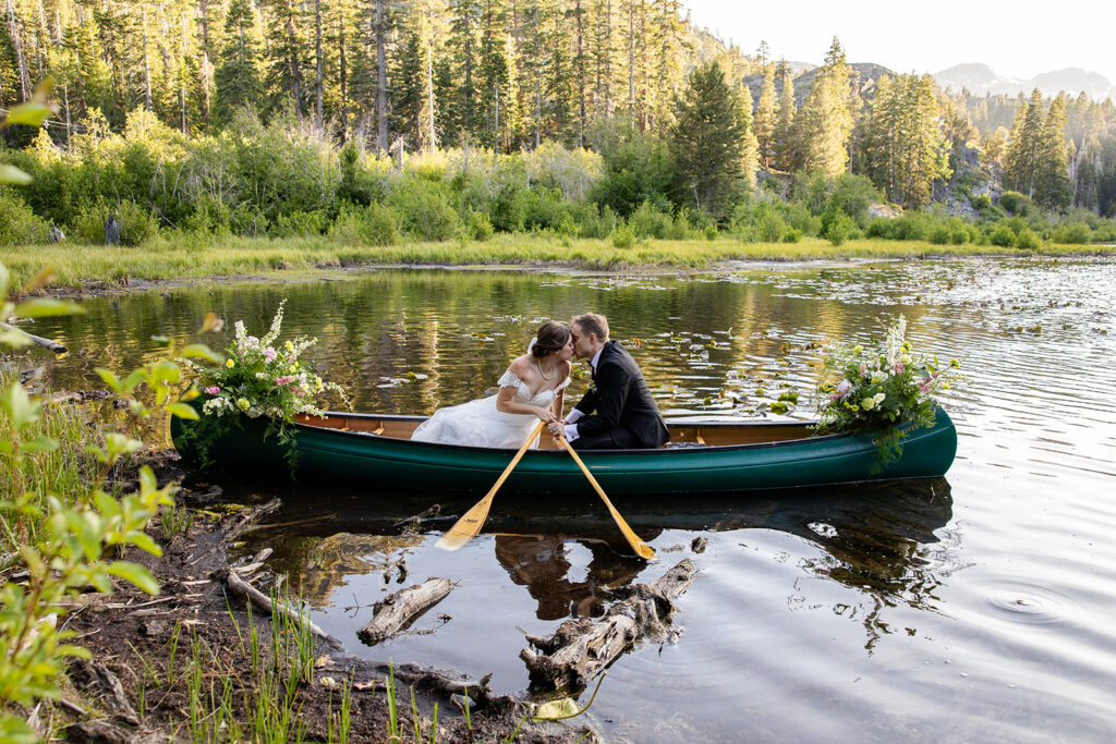 Bride and groom paddling in a canoe during their Lake Tahoe canoe wedding photos at Lily Lake.