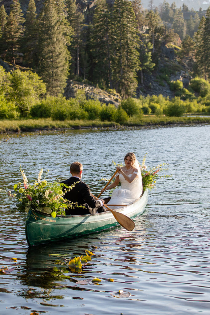Bride and groom paddling in a canoe during their Lake Tahoe canoe wedding photos at Lily Lake.
