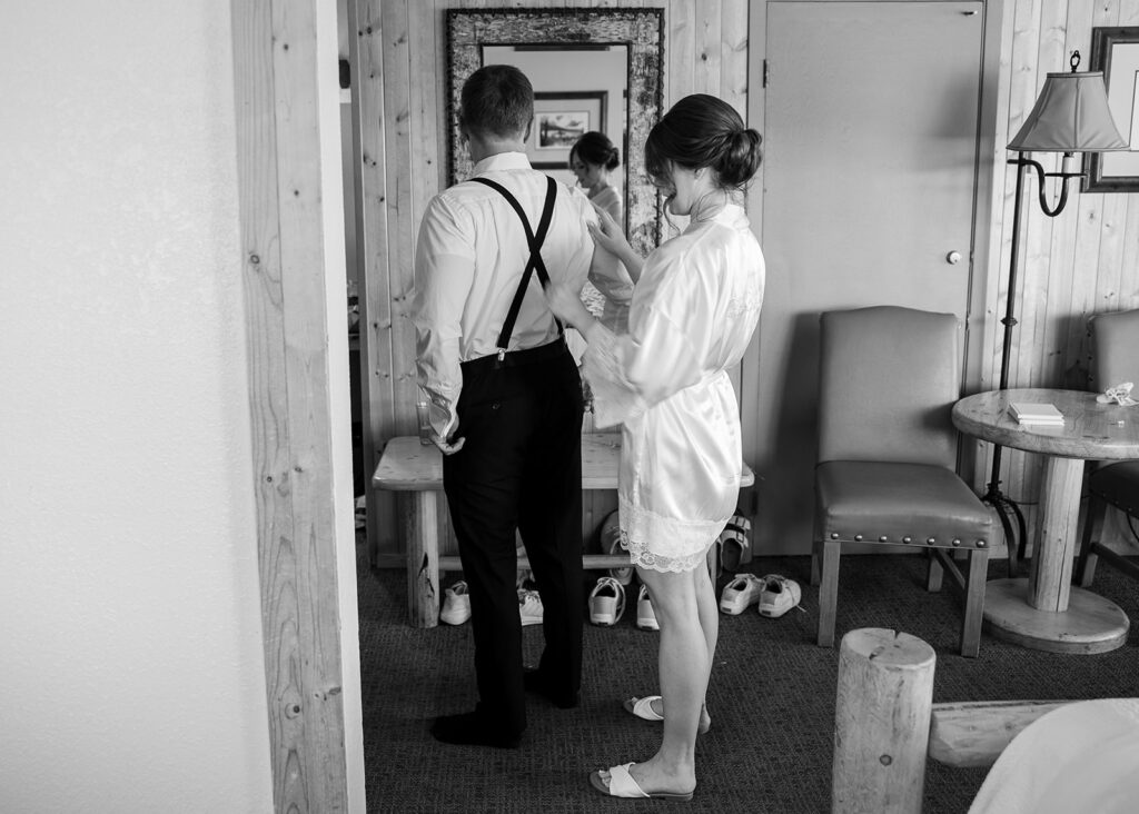 bride and groom helping each other get ready at the airbnb