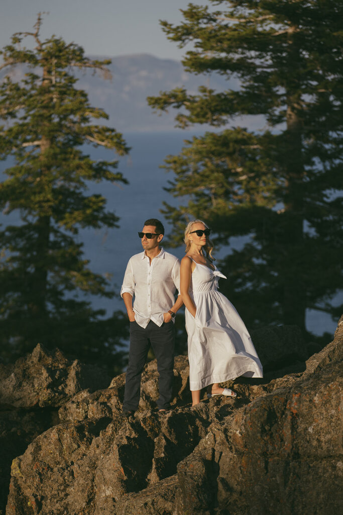 couple standing back to back, wearing sunglasses and looking cool, for their mountain engagement photoshoot in lake tahoe