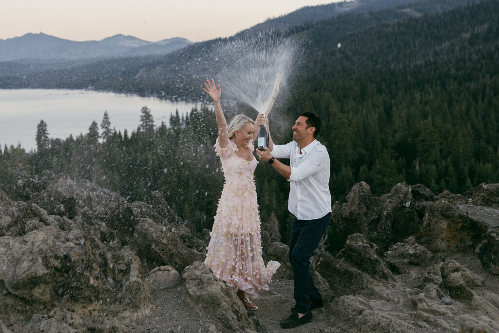 newly engaged couple popping champagne during their engagement session at eagle rock, lake tahoe
