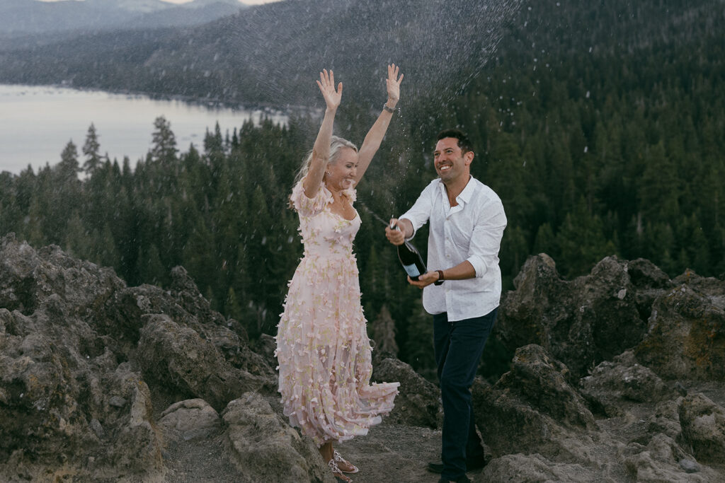 newly engaged couple popping champagne during their engagement session at eagle rock, lake tahoe