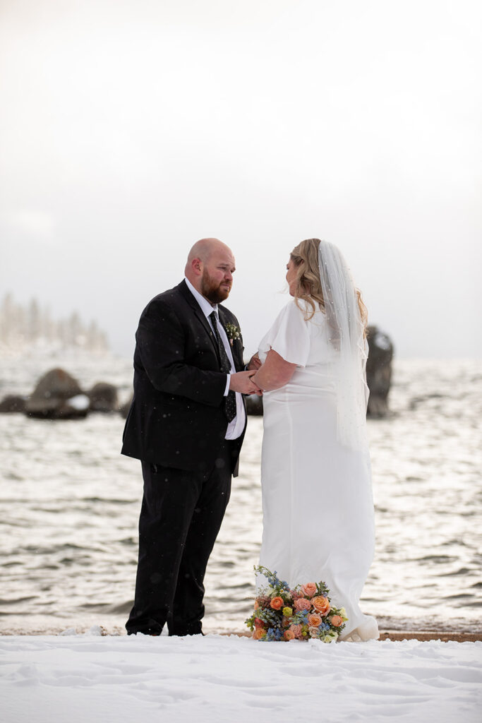 bride and groom exchanging private vows during their snowy spring micro wedding ceremony at lake tahoe 