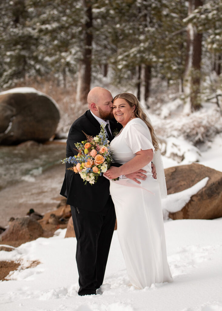 bride and groom standing in some snow during their snowy spring micro wedding in Lake Tahoe