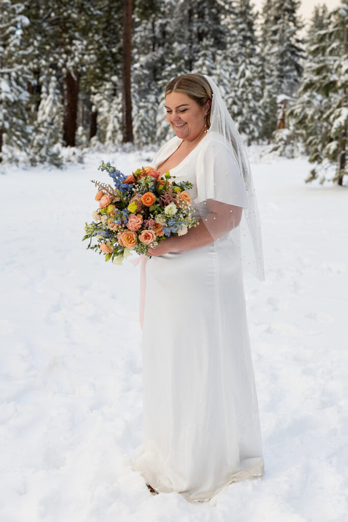 bride standing in some snow during their snowy spring micro wedding in Lake Tahoe
