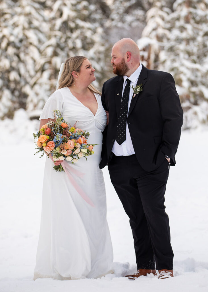 bride and groom standing in some snow during their snowy spring micro wedding in Lake Tahoe