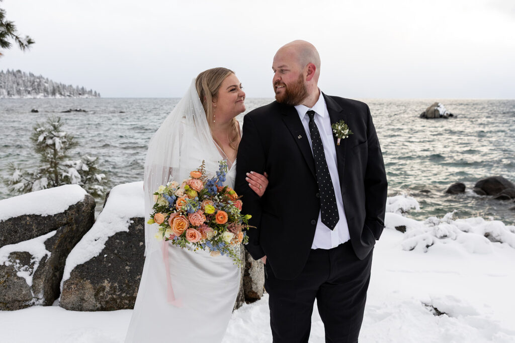 bride and groom standing in some snow during their snowy spring micro wedding in Lake Tahoe