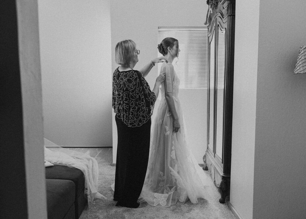 mom helping bride into her dress