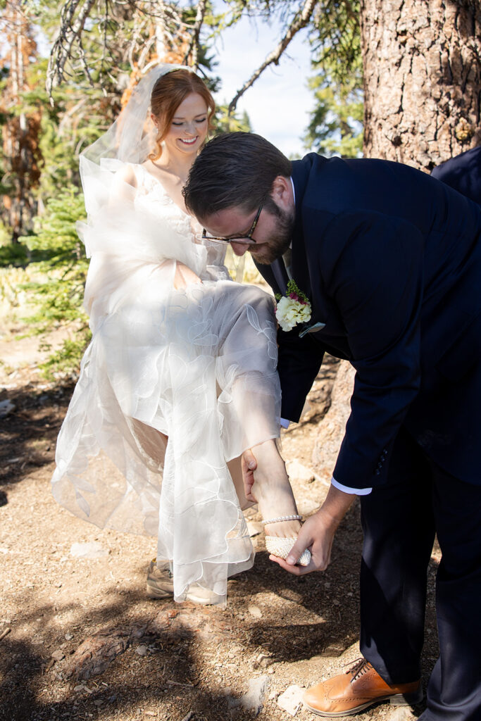 groom helping bride change her shoes