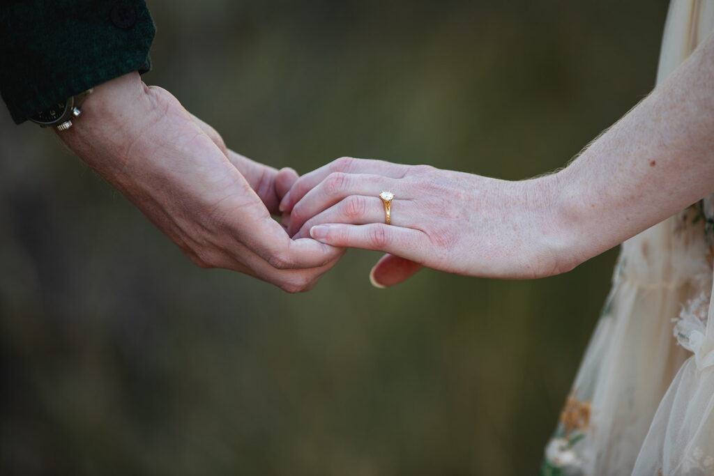 close up of couple holding hands with engagement ring showing